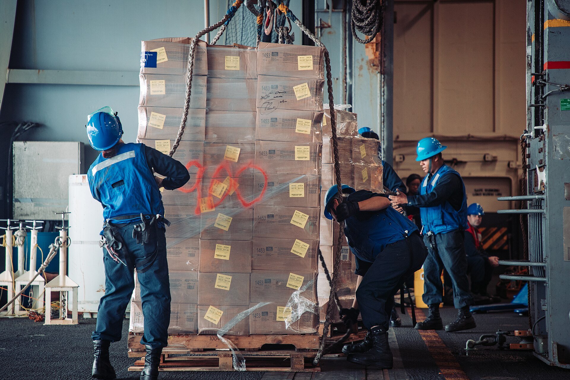 Sailors unload cargo during a resupply at sea aboard USS George Washington, May 2024. U.S. Navy photo, public domain, via Wikimedia Commons.